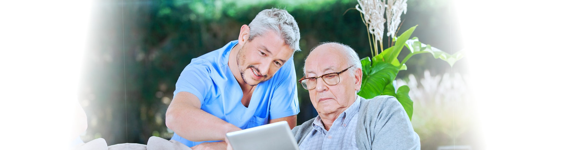 senior man and caregiver using a tablet